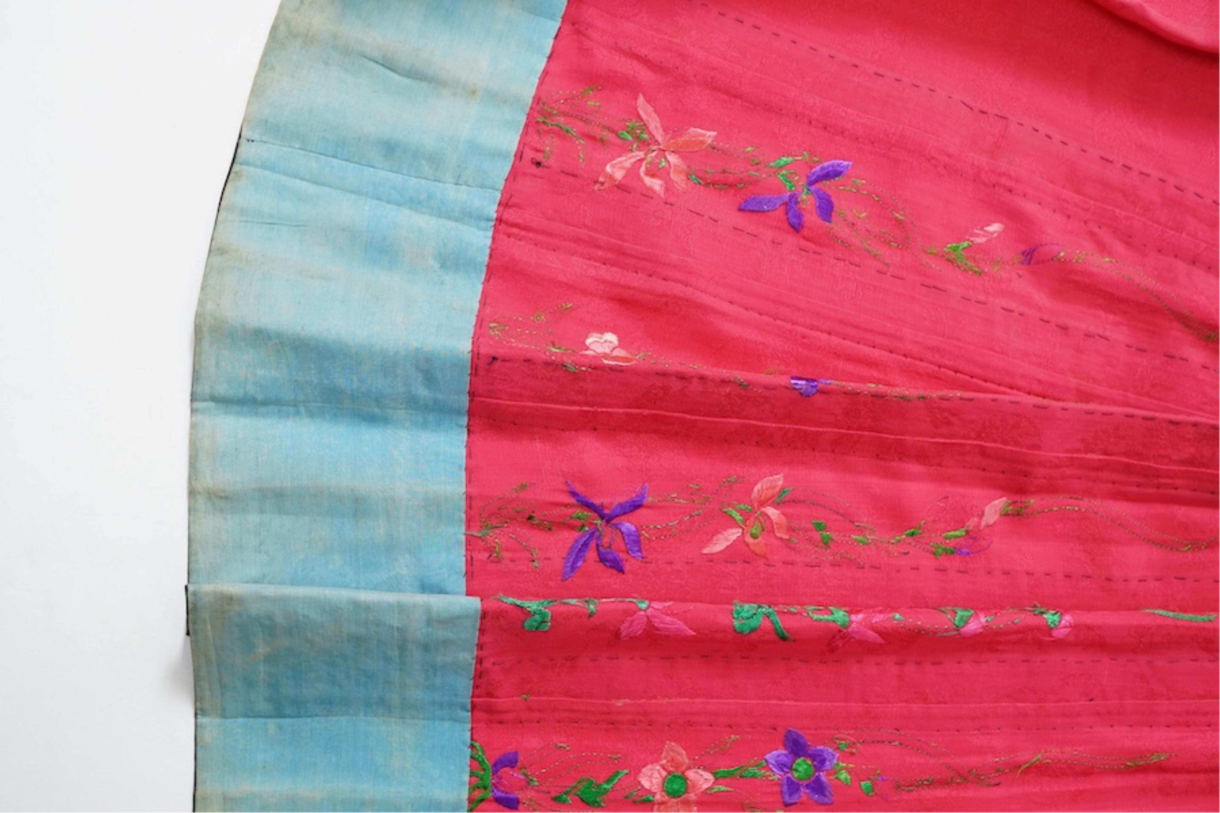 Two late 19th early 20th century Chinese wedding skirts. Made with pink silk damask, embroidered with large decorative silk floral and butterfly front panels bordered by blue embroidered black silk borders between pleats